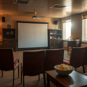 A community room set up for an afternoon film screening, chairs facing a screen and a bowl of popcorn